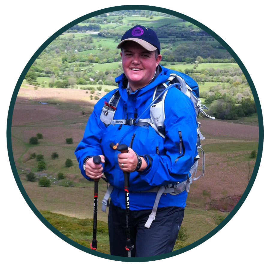 man walking in hills with hiking equipment