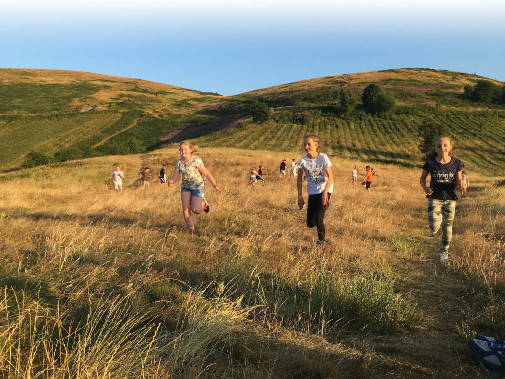 Children running across Malvern Hills on summers day