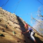 Boy on wooden climbing wall on sunny day