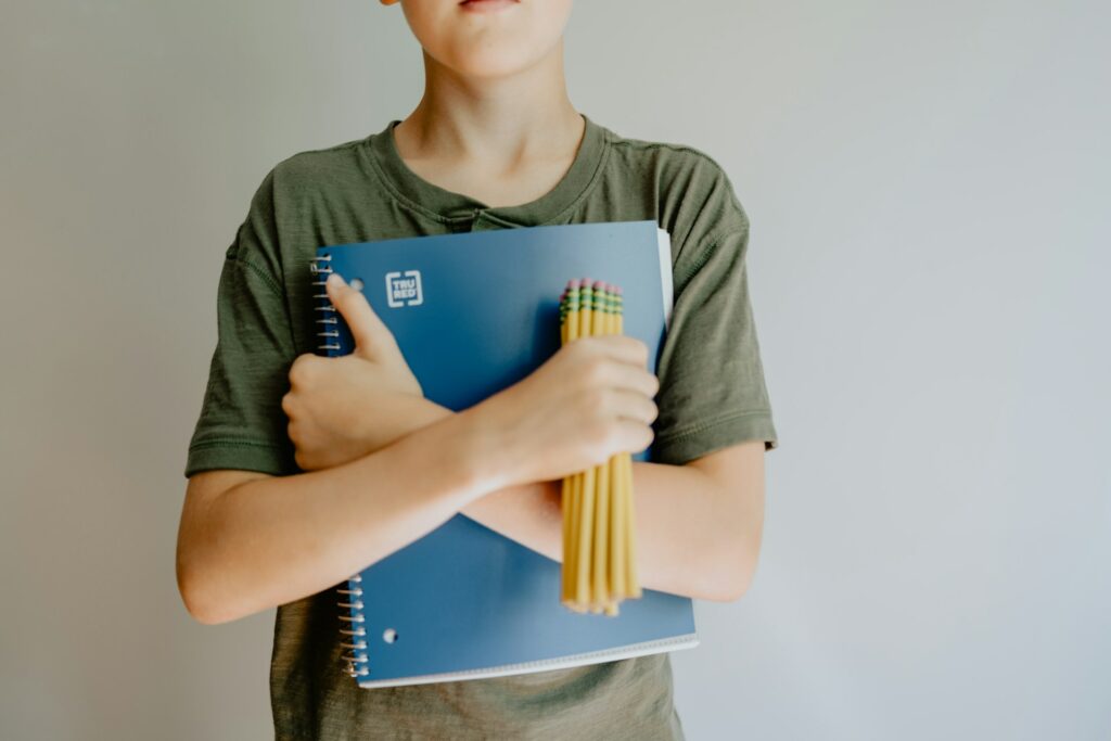 Child holding school books and pencils