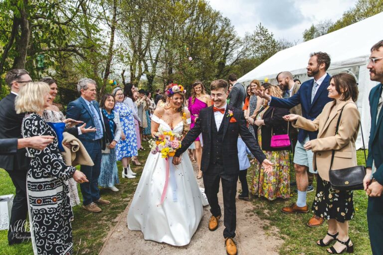 Couple on their wedding day in the woodlands surrounded by friends and family